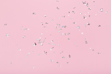 Silver glitter confetti sparkles on pastel pink background. Flat lay, top view. Holiday, festive, party backdrop.
