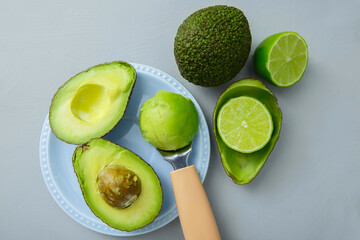 Fresh avocados with pulp on a saucer, with a spoon and fresh halves of green lime. Top view