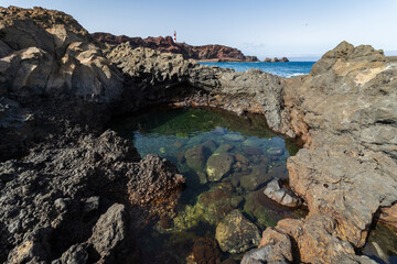 Rocky coast of the Atlantic Ocean at Cape Teno. A lighthouse in the background. Tenerife. Canary Islands. Spain.