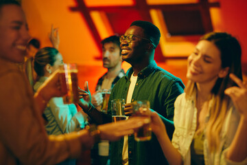 Young African American man has fun and dances on night party in bar.