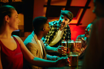 Cheerful man toasts with his friends in bar during their night out.
