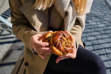 Woman's Hand Holding Delicious Swedish Buns, Kanelbullar. Baking close-up. A sweet snack outdoors. Traditional Swedish pastries