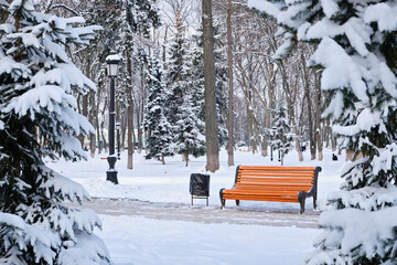 orange bench in the park in the snow in winter