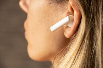 Wireless TWS white headphones in a girl's ear close-up, listening to music in headphones