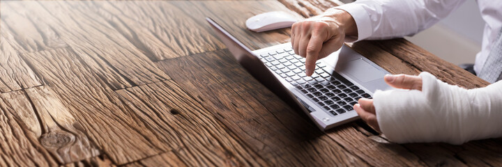 Businessperson With Hand Injury Using Laptop