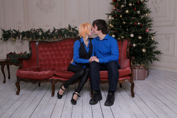happy couple in love at home on sofa. Christmas tree on background