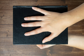 a woman holds a black book in her hands	