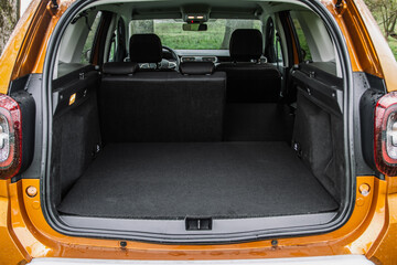 Huge, clean and empty car trunk of a modern compact suv. Rear view of a SUV car with open trunk and one folded seat. Car trunk interior. - obrazy, fototapety, plakaty