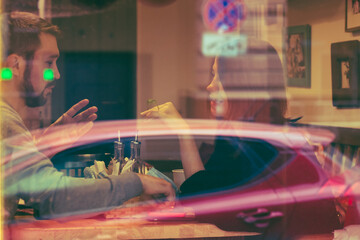 photograph of a young couple behind the glass of a cafe