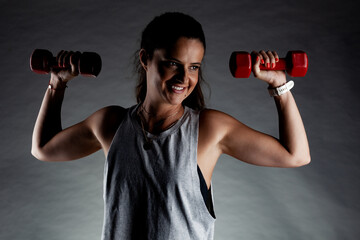 Fototapeta na wymiar Fitness girl posing and lifting weights. Positive smiling expression.