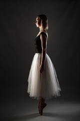ballerina with a white dress and black top posing on gray background. © Nikola Spasenoski