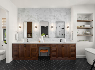 Gorgeous ensuite bathroom in luxury home. Features black herringbone tile floor, marble tile backsplash and wall, double vanity and sconce lights.