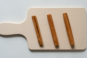 three cinnamon sticks on a wooden background