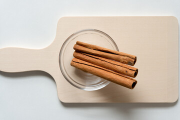 cinnamon sticks in a glass bowl on a wooden surface