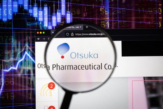 Otsuka company logo on a website with blurry stock market developments in the background, seen on a computer screen through a magnifying glass	