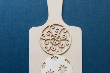 fancy laser cut wooden shape (circle) and christmas ball on a wooden paddle on blue paper background