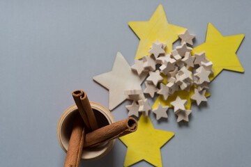 cinnamon sticks in a wooden cup with large and small stars on a gray paper background