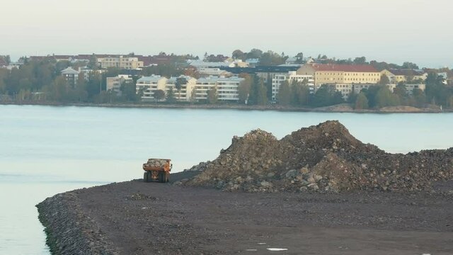 A dumptruck carrying the big rocks on the back from the construction site near the harbor in Helsinki Finland