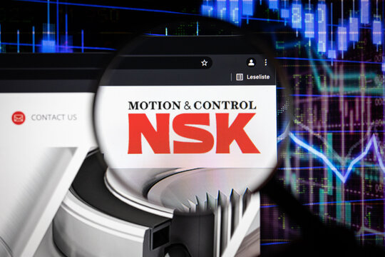 NSK company logo on a website with blurry stock market graphs in the background, seen on a computer screen through a magnifying glass.