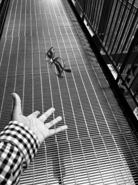 Black and white hand throwing black framed glasses above metal platform