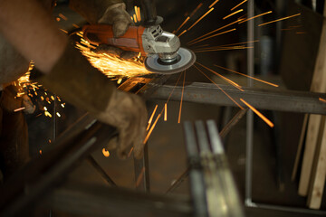 Obraz premium Work grinding machine. Sparks from the force of friction. A man in a workshop processes metal.