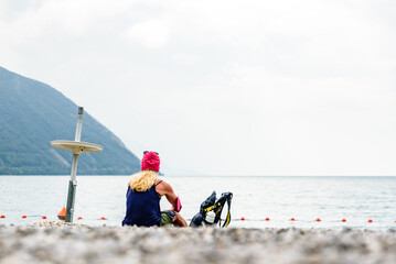 A sportswoman rests on her back on the shore of a lake.