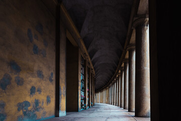 Hallway with monumental columns framed by the dark shadows of a cemetery.