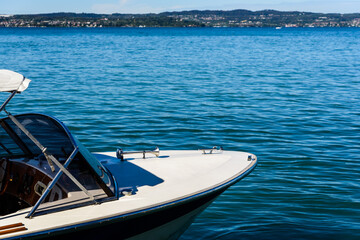 The bow of a small boat on the blue water of a lake with copy space.