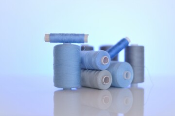 thread spools. Sewing threads set.Blue and gray thread spools on a light blue background.Needlework...