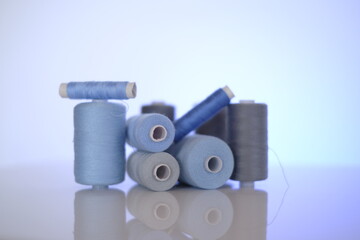 thread spools. Sewing threads set.Blue and gray thread spools on a light blue background.Needlework...