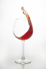 red wine splashes out of a glass on a light background. alcoholism and addiction. drinks for the holiday