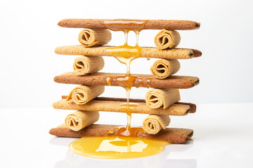 Fresh flower honey flows and drips onto herdry crispy cookie sticks. Dessert snack food.