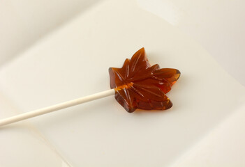 Closeup of maple leaf maple syrup lollipop on white dessert plate 
