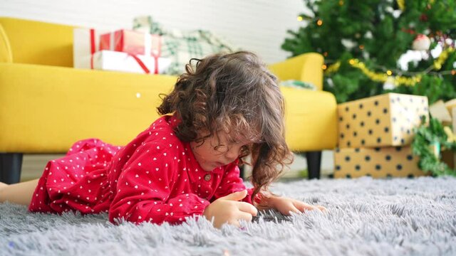 4K Happy family celebration Christmas eve and New Year holiday together at home. Little child girl kid lying on the floor in living room playing games or watching cartoon on smartphone.with happiness