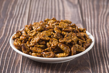Fried Silkworm chrysalis  in a plate on table