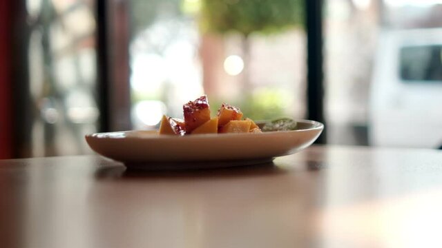 Plate of chopped mango with Mexican chamoy sauce and blurry background