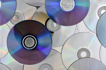 Lots of used laser CDs and DVDs on the surface of the table, technological background