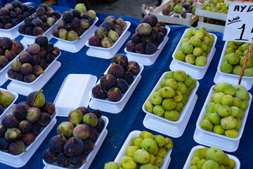 Fresh figs packaged on plastic substrates on the counter on farmer's market. Green and purple figs. Healthy eating