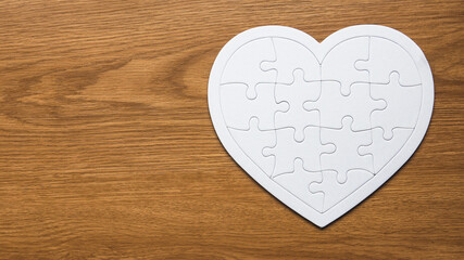 Top view of heart or love shape jigsaw puzzle on a wooden background.