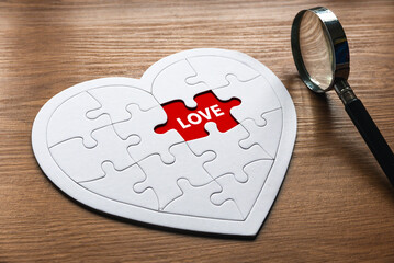 Selective focus of magnifying glass and heart shape jigsaw puzzle  with a red empty space written...