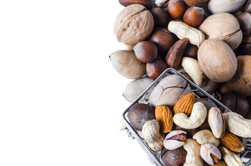 A cart full of different nuts and a mountain of different nuts on a white background. Assorted different types of nuts on a light background.