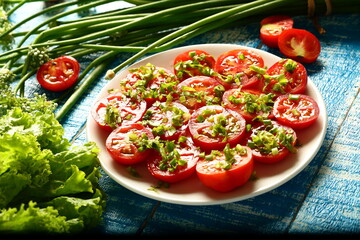 Healthy vegetarian diet meal- homemade organic tomato salad with fresh herbs and greens.
