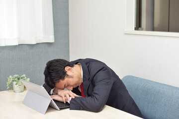 A young Asian man during telework at home sleeps on the desk for short time