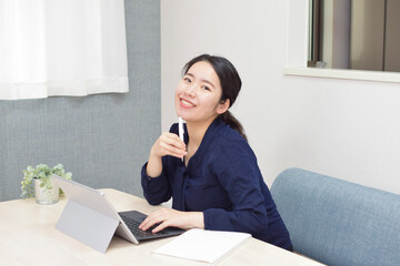 A young Asian woman works at home as telework and shows her smile