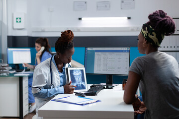 African american radiologist doctor showing bones radiography using tablet computer discussing xray...