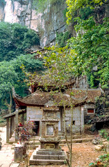 Eingescanntes Diapositiv einer historischen Farbaufnahme einer buddhistischen Tempelanlage am Fusse eines Felsens in Nordvietnam