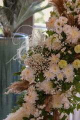 Triangular wooden arch with composition of pampasian grass, dianthus and roses.