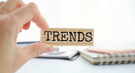 TRENDS text on wooden block with hand on wooden background