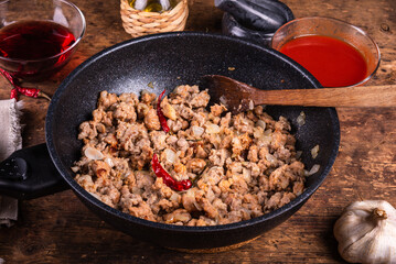 Sausage, onion and pepper ragout - sausage ragout in a pan on the table with ingredients for making the sauce