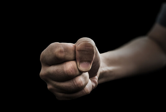 Selective focus shot of a male's fist on a black background